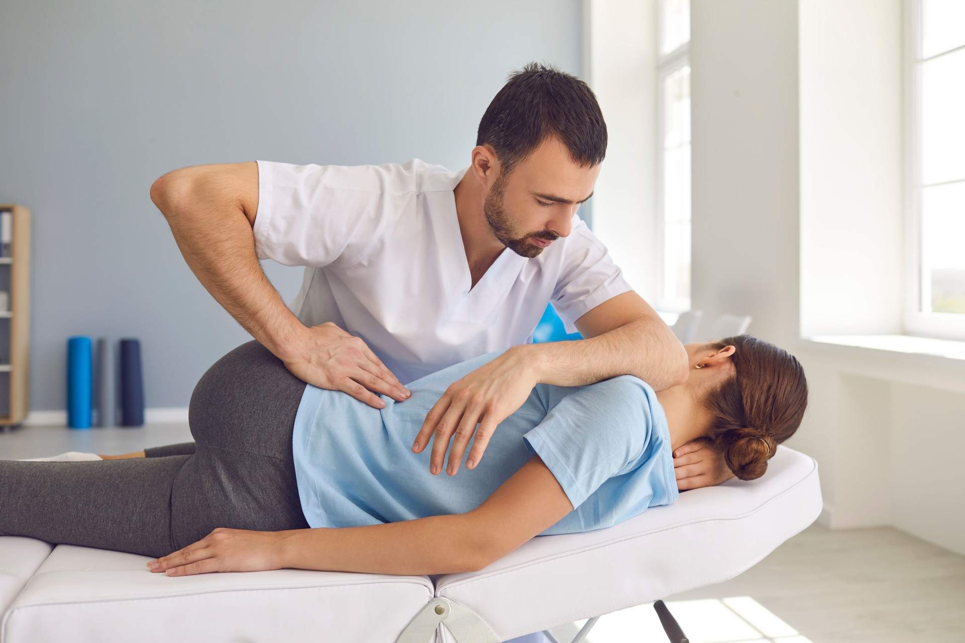 Mann Arzt Chiropraktiker oder Osteopath Fixierung liegende Frauen zurück in manuelle Therapie Klinik